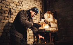 The blacksmith manually forging the red-hot metal